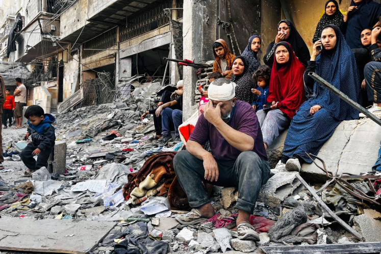 An injured man reacts while sitting on the rubble of a building hit by an Israeli strike in Beit Lahia, in the northern Gaza Strip, on October 29, 2024, amid the ongoing war between Israel and Hamas. Gaza's civil defense agency said on October 29 that an overnight Israeli air strike killed more than 55 people in a residential building in the northern district of Beit Lahia. 