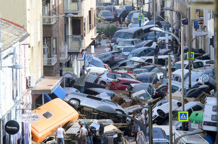 Pedestrians stand next to  piled up cars following deadly floods in Sedavi, south of Valencia, eastern Spain, on October 30, 2024.