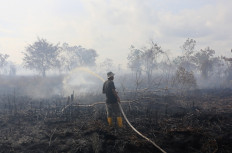 A firefighter sprays water on burning peatland in Deuah village, West Aceh regency, Aceh on Oct. 26, 2024.