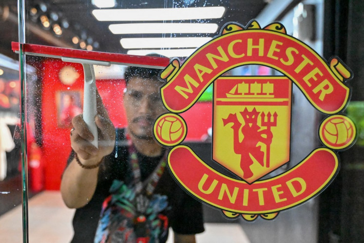 Zulfikar Rahman, Store Officer & Graphic Designer fan shop klub sepak bola Manchester United Indonesia dan base camp komunitas United Army, melakukan pembersihan saat toko dibuka untuk bisnis di Jakarta pada 29 Oktober 2024.