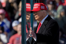 Republican presidential nominee and former U.S. President Donald Trump touches the protective glass, during a campaign rally, in Lititz, Pennsylvania, U.S. November 3, 2024. 