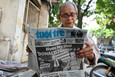 A man reads a Vietnamese newspaper in Hanoi on November 7, 2024, showing the reaction to the re-election of US President-elect Donald Trump.