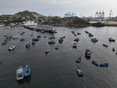 Aerial view of traditional fishing boats anchored in the town's harbor with the Chancay “megaport“ cranes in the background, 78 kilometers north of the Peruvian capital Lima, on October 29, 2024. 
