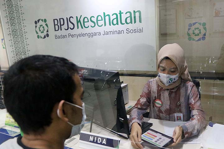 An employee serves a customer at a Jakarta branch of the Health Care and Social Security Agency (BPJS Kesehatan). 