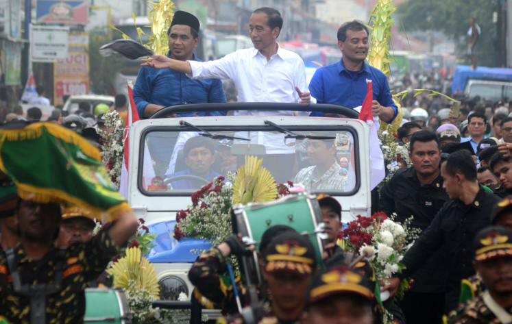 Former president Joko “Jokowi” Widodo (center), alongside Central Java gubernatorial candidate pair Ahmad Luthfi (right) and Taj Yasin (left), distributes T-shirts during a campaign parade on Jl. Tegal in Purwokerto, Central Java, on Nov. 16, 2024.