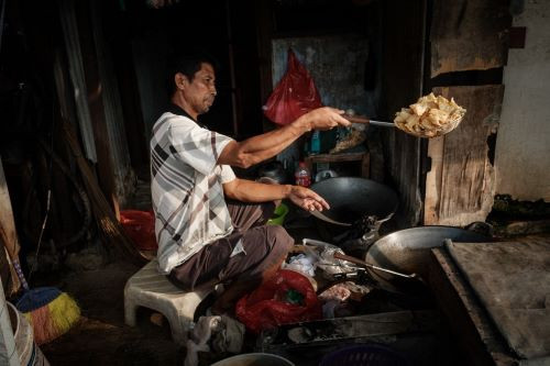A roadside vendor prepares food on May 12, 2024, to sell at his stall next to a railway in Jakarta.