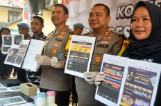 Bogor city Police chief Sr. Comr. Bismo Teguh Prakoso (thrid right) holds seized evidence from the arrest of online gambling website developers during a press briefing at the Bogor city Police headquarters in West Java on Nov. 8, 2024. 
