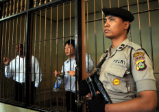 A policeman stands guard next to a detention room where Australians Myuran Sukumaran (left) and Andrew Chan (center), members of the so called Bali Nine gang, wait for their trial in Denpasar on the island of Bali on October 8, 2010. A prison chief testified on October 8, that two Australian drug smugglers on death row have given great contribution in teaching fellow inmates and should not be executed. Chan and Sukumaran, members of the so-called Bali Nine gang, are seeking 20 years to life in prison for a 2005 attempt to smuggle 8.3 kilograms of heroin into Australia from Bali. 