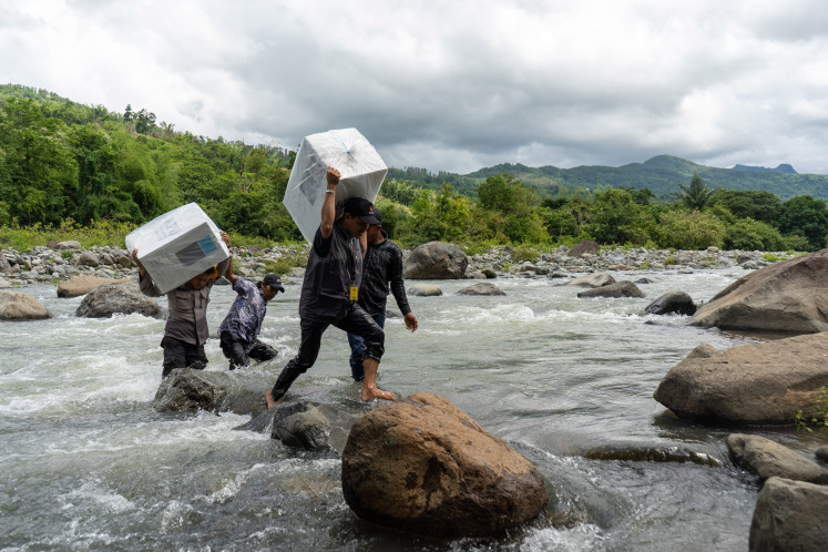 Getting it done: Police personnel and Bawaslu officers cross the Tompobulu River to distribute logistics for the 2024 Regional Elections to Bonto Manurung Village, Maros Regency, South Sulawesi, on Tuesday. The route was chosen to cut the travel time for logistics distribution by up to two hours to TPS 01 Dusun Makmur, which has a Permanent Voter List (DPT) of 176 people. 