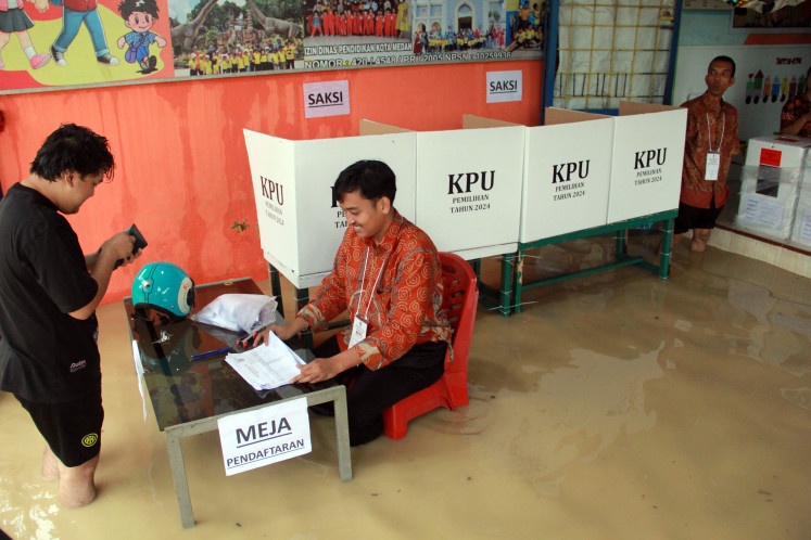 Poll workers assist a voter at polling station (TPS) 9 in Tanjung Gusta sub-district, Medan, North Sumatra, on Wednesday, Nov. 27, 2024. The city’s General Elections Commission (KPU) says 45 TPS have to reschedule the voting process due to the flooding. 