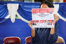 A woman shows a Jakarta gubernatorial election ballot on Nov. 27, 2024, before voting at a polling station in Jakarta.