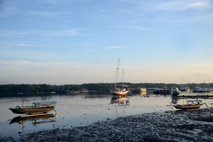 A two-masted sailing boat is anchored among 'jukung' traditional fishing boats on March 13, 2021, in a shallow bay at Serangan Island in Denpasar, Bali.