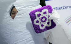 An activist looks out from an inflatable polar bear costume while holding a sign with a symbol representing nuclear energy as she participates in an action called “Spreading Awareness with a Smile: The Banana Radiation Campaign“ on Nov. 16, 2024, at the United Nations Climate Change Conference (COP29) in Baku. 
