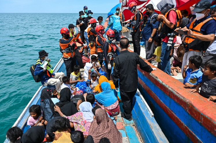 People rescue Rohingya refugees from a boat after a week anchored ashore off the coast of Labuhan Haji in southern Aceh on Oct. 24, 2024. 