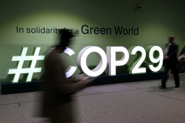 People walk past a #COP29 sign on Nov. 21 during the 2024 United Nations Climate Change Conference (COP29) in the Azerbaijani capital Baku.