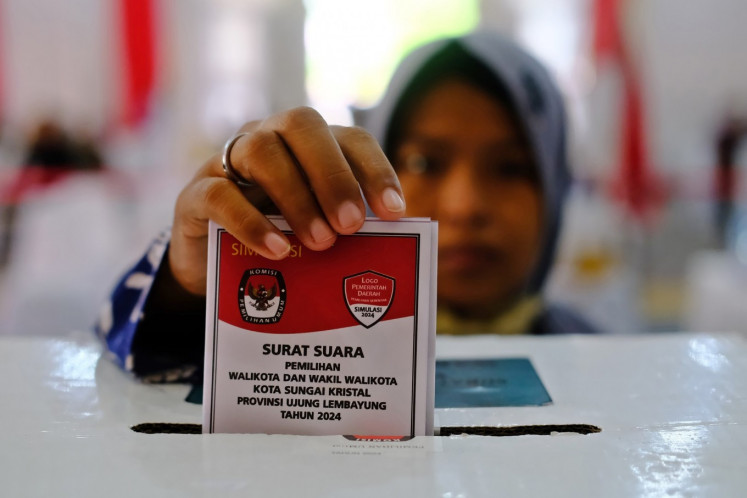 A woman places her “vote” into a ballot box on Nov. 13 during a simulation in Pontianak, West Kalimantan, ahead of the 2024 simultaneous regional head elections on Nov. 27.