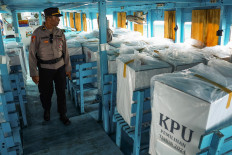 A police officer inspects ballot boxes for the 2024 regional head elections aboard a boat on Nov. 24 at Paotere Port in Makassar, South Sulawesi, prior to their distribution under police escort to 21 polling stations on five islands in Sangkarrang district.