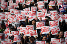 Protesters hold up signs that read “Step down President Yoon Suk Yeol“ as people and lawmakers attend a rally to condemn South Korean President’s surprise declarations of the martial law last night and to call for his resignation, at the national assembly in Seoul, South Korea, on Wednesday, December 4, 2024. 
