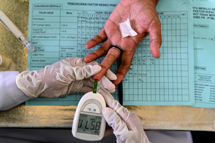 An elderly woman gets her blood tested during a drive to provide medical check-ups for hypertension, cholesterol and diabetes at an integrated services post (posyandu) in Banda Aceh, Aceh on Dec. 15, 2021.