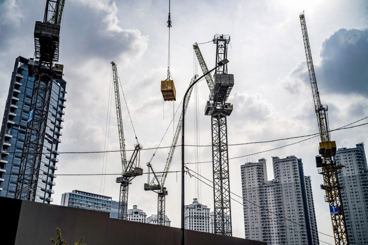 Construction cranes operate near skyscrapers at a business district in Jakarta on Nov. 13, 2024.