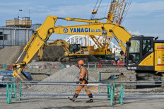 A worker walks past a backhoe as construction continues at the site of the 2025 Expo on Yumeshima island, an area of reclaimed land in Osaka, Japan, on Sept. 14, 2023. The World Expo is scheduled to open on April 13, 2025.