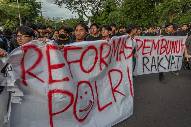 Civil society activists and university students hold a banner that reads “Police reform“ (left) and “People's killer“ during a protest in front of the Central Java Police in Semarang on Nov. 28, 2024. The protesters demand the police to investigate thoroughly the police officer who shot a 17-year-old high school student to death on the early morning of Nov. 24.