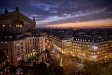 Christmas lights are pictured at the Galeries Lafayette department store in Paris with the Eiffel Tower seen in the background at sunset on Nov. 25, 2024.