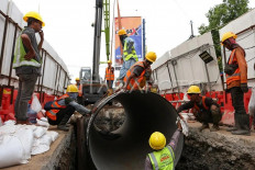 Workers move a pipe using a crane on Jl. Jatiwaringin in Pondok Gede, Bekasi city, West Java, on Nov. 11, 2024. Jakarta administration-owned tap water company PT PAM Jaya is installing 1.6-meter diameter distribution pipes to reach a 100-percent coverage of tap water in Jakarta by 2030.