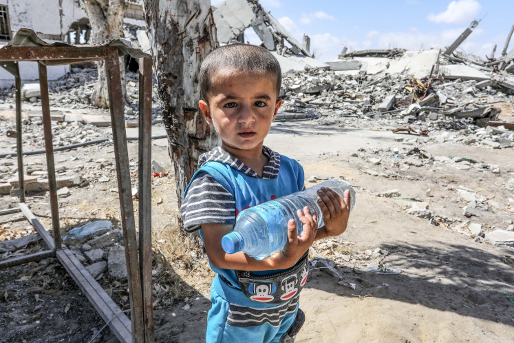 A Palestinian boy collects drinking water in this July photo in Gaza, where the prospect of mass starvation looms large.