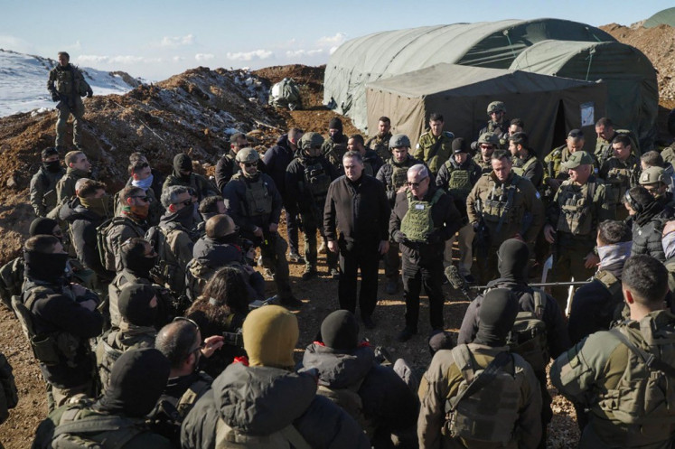 This handout picture released by the Government Press Office (GPO) shows Israeli Prime Minister Benjamin Netanyahu (C-R) and Defence Minister Israel Katz (C-L) standing among members of the Israeli army at Mount Hermon in the annexed Golan Heights, on December 17, 2024.