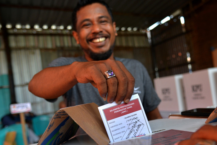 A voter casts his ballot into a ballot box at a polling station during a revote on Dec. 3, 2024, for the 2024 simultaneous regional elections in Makassar, South Sulawesi.