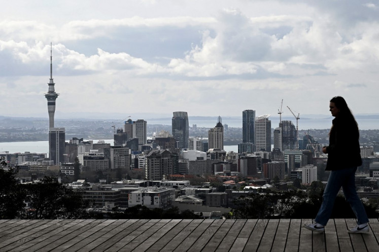 A tourist visits Maungawhau/Mount Eden, a dormant volcano and the highest natural point in Auckland, on Aug. 7, 2023, with views of the city skyline and its harbors.