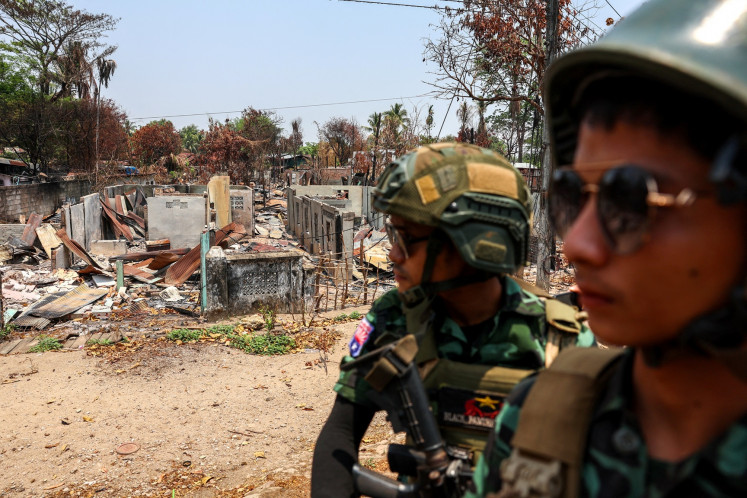 Soldiers from the Karen National Liberation Army (KNLA) patrol on a vehicle next to an area destroyed by Myanmar's airstrike in Myawaddy, the Thailand-Myanmar border town under the control of a coalition of rebel forces led by the Karen National Union, in Myanmar on April 15, 2024.