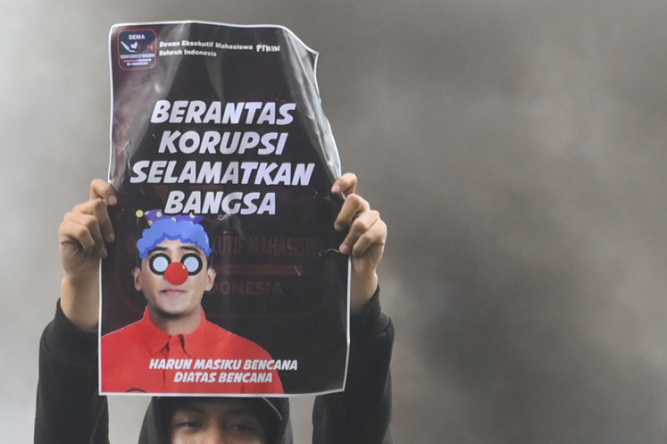 A protester holds up a poster that reads “Fight the corruption to save the nation“ during a protest in front of the Corruption Eradication Commission (KPK) headquarters in Jakarta on Dec. 18, 2024. The protesters demand the antigraft body to quickly arrest and prosecute Harun Masiku, an Indonesian Democratic Party of Struggle (PDI-P) politician who has been at large after being named suspect in a graft case in 2020.