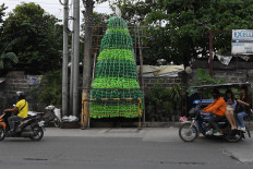 Motorists and commuters ride past a Christmas tree made from recycled plastic bottles on Nov. 7, 2024, in Manila.
