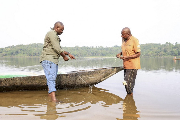 Aristide Takoukam Kamla (left), a marine biologist who specializes in the African manatee, talks with a fisherman in Dizangue, on Dec. 11, 2024. Ever since his first hard-won sightings of African manatees, award-winning marine biologist Aristide Takoukam Kamla has been devoted to protecting the little known and at risk African manatees, a mammal found in fresh water along the coast of western Africa, such as in Cameroon's vast Lake Ossa where the researcher first saw them more than 10 years ago.