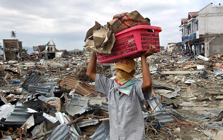 A man carries belongings from his damaged shop in Banda Aceh, Aceh on Dec. 31, 2004 after the 9.1-magnitude earthquake and resulting tsunami hit the area.