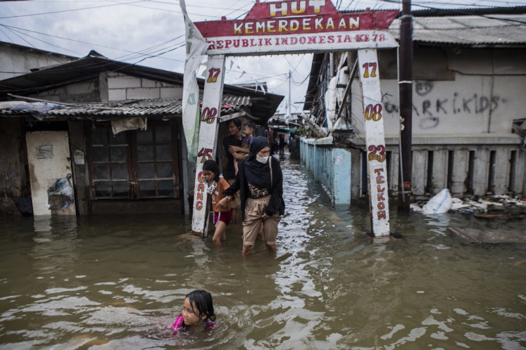 People wade through floodwaters after a tidal flood at Muara Angke in North Jakarta on Dec. 15, 2024.