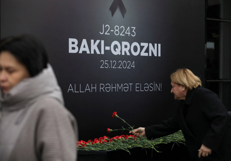 People lay flowers to commemorate victims of an Azerbaijan Airlines' Embraer passenger plane crash near the Kazakh city of Aktau at a memorial installed outside an airport in Baku, Azerbaijan, on Dec. 26, 2024.