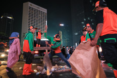 Workers from the city’s sanitation agency, dubbed “Pasukan Oranye” (orange troops) for their distinctive uniforms, cleans discarded food, beverage bottles and other roadside litter around the Hotel Indonesia traffic circle in Central Jakarta on New Year’s Day 2025.