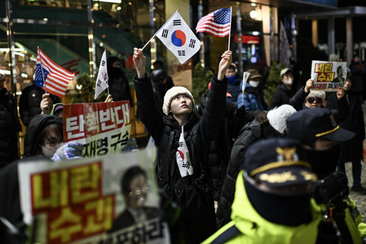 A supporter of South Korea's impeached president Yoon Suk Yeol waves flags of South Korea and the United States near the location where an anti-Yoon rally is taking place in Seoul on January 2, 2025. 