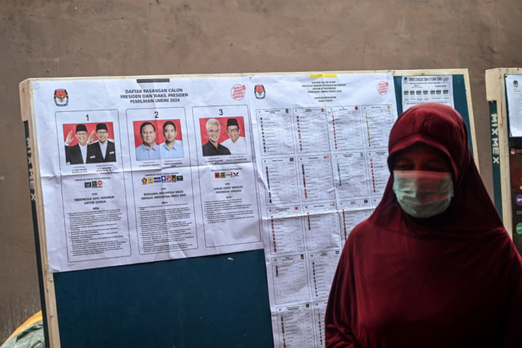 A woman walks past a candidate list at a polling station during a revote in Surabaya, East Java on Feb. 24, 2024, following logistical problems which affected some ten polling stations across the city during the Feb. 14 presidential and legislative elections.