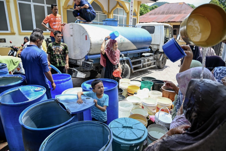 Women cool off from buckets filled with water supplied by local officials amid the drought season in Lhoknga, Aceh, on May 12, 2024.