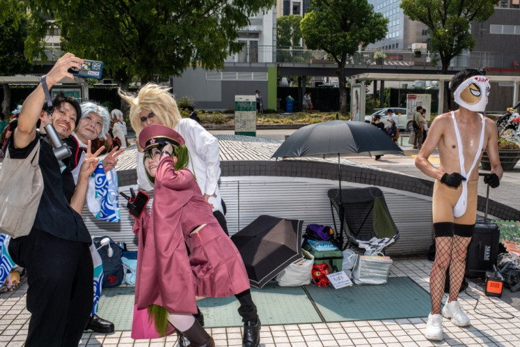 A man (left) takes selfie pictures with cosplay fans outside the World Cosplay Summit in Nagoya on Aug. 3, 2024.