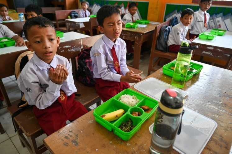 Students pray on Jan. 6 before eating their lunch on the first day of the free nutritious meal program at an elementary school in Banda Aceh, Aceh. Indonesia launched the ambitious US$4.3 billion free meals program on Jan. 6 to combat stunting caused by malnutrition, a key election promise of President Prabowo Subianto.