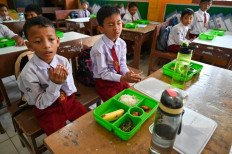 Students pray before eating their lunch on the first day of a free-meal program at an elementary school in Banda Aceh, Aceh, on January 6, 2025. Indonesia launched an ambitious US$4.3 billion free-meal program on January 6 to combat stunted growth due to malnutrition, a key election promise of President Prabowo Subianto.