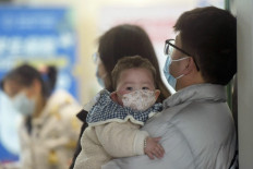 A baby wearing a face mask waits with family members at the pediatric department of a hospital in Hangzhou, eastern China's Zhejiang province, on January 6, 2025. 