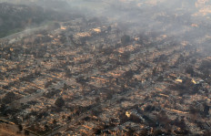In this aerial view taken from a helicopter, burned homes are seen from above during the Palisades fire near the Pacific Palisades neighborhood of Los Angeles, California, US, on January 9, 2025. Massive wildfires that engulfed whole neighborhoods and displaced thousands in Los Angeles remained totally uncontained January 9, 2025, authorities said, as US National Guard soldiers readied to hit the streets to help quell disorder. Swaths of the United States' second-largest city lay in ruins, with smoke blanketing the sky and an acrid smell pervading almost every building.