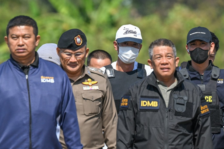 Ekalak Paenoi (center), a suspect in the alleged killing of Lim Kimya, a former lawmaker of the dissolved Cambodia National Rescue Party (CNRP), is escorted by police officers upon his return from Cambodia on Jan. 11, 2025, at the police airport in Bangkok.