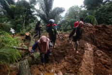 People walk through the site of a landslide triggered by heavy rain two days ago in Mudal village, near Pekalongan city in Central Java on January 22, 2025. 